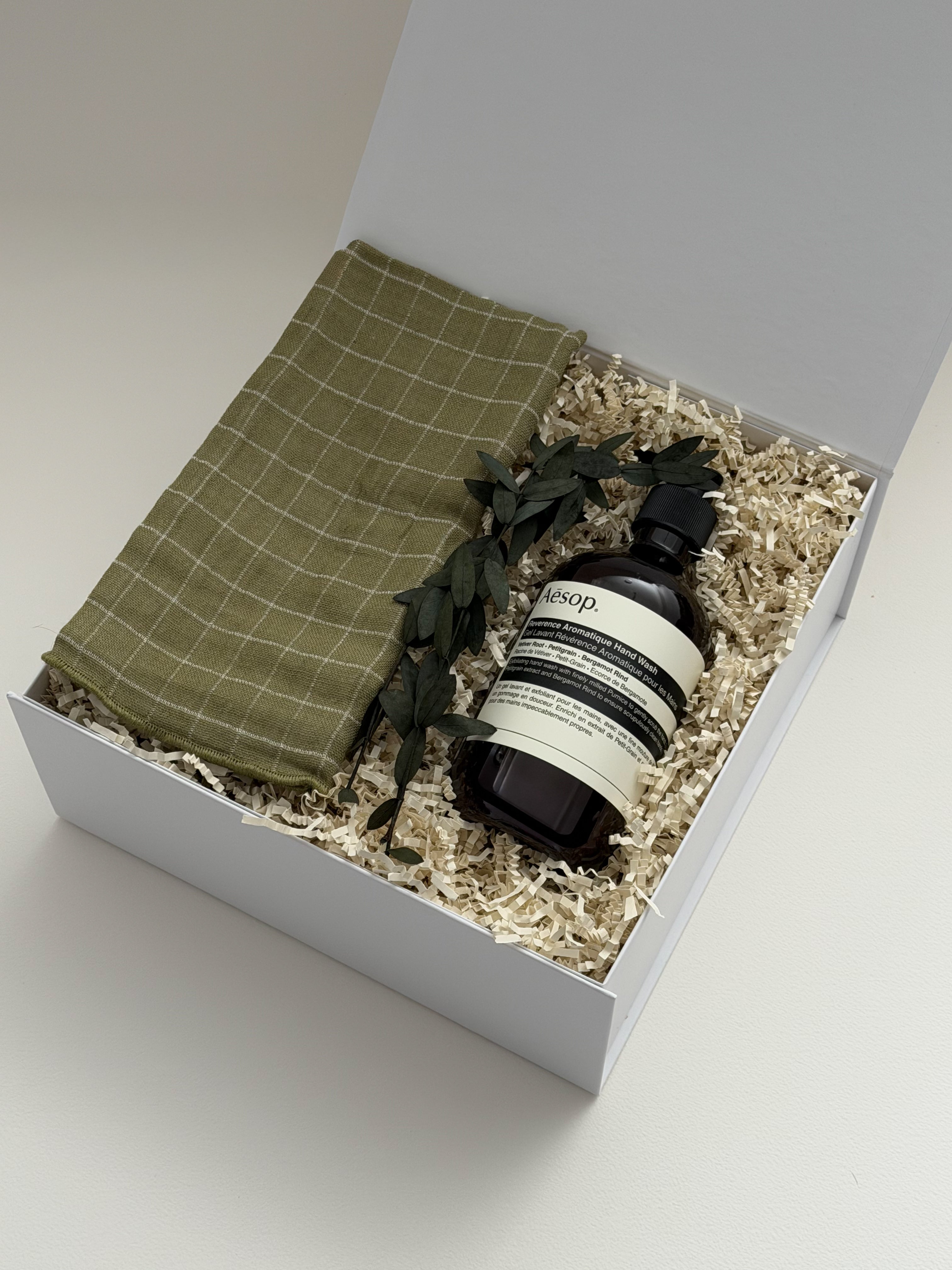 Gift set with a green hand towel and Aesop soap bottle in a white box.