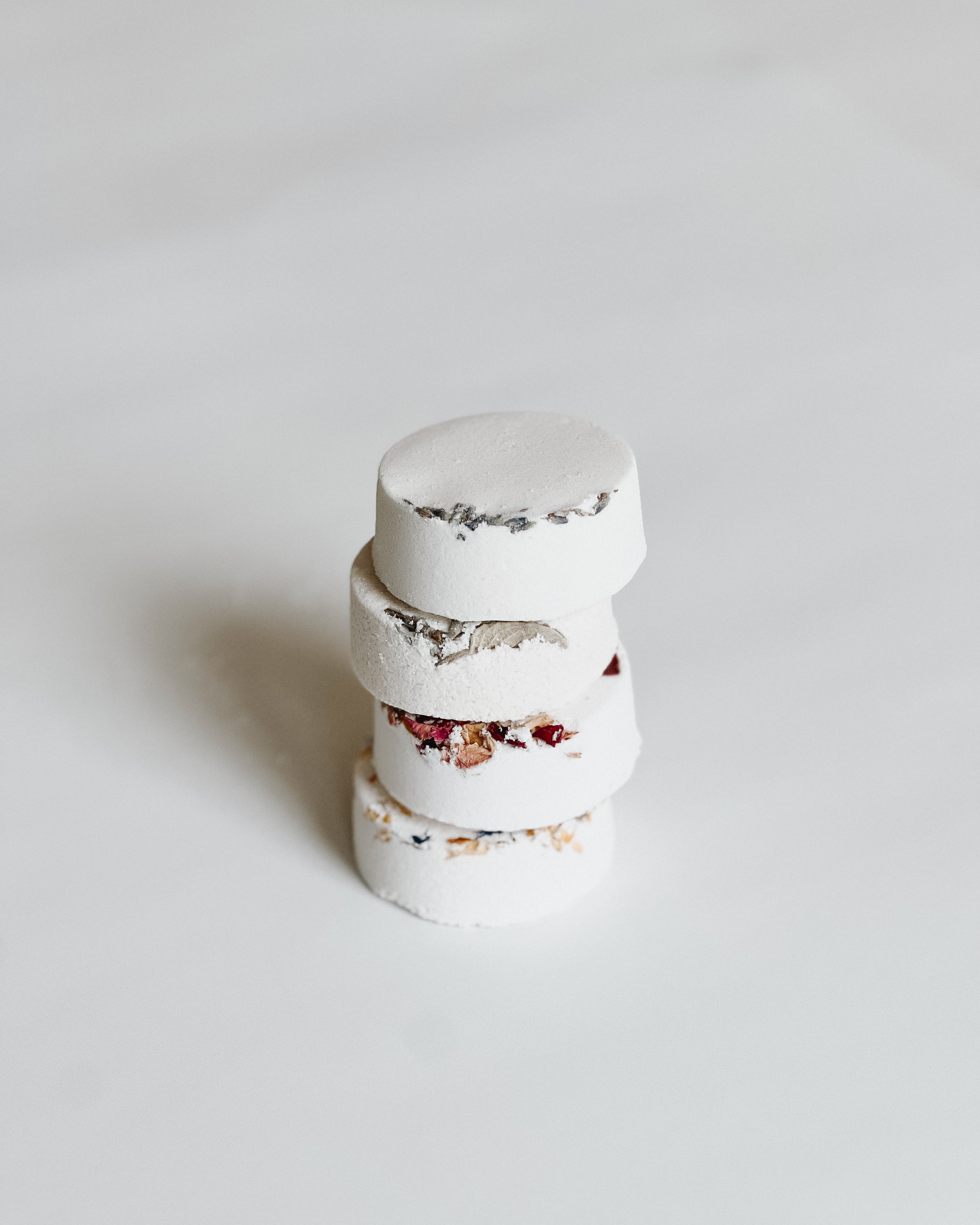 Close-up of stacked Aqua Studio shower steamers with dried floral accents, a self-care product featured in Muse Baskets and Co. gift baskets