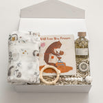 The Arrival gender-neutral new baby gift box by Muse Baskets and Co. with hedgehog swaddle, storybook, teething ring, pacifier clip and care products for mama.