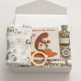 The Arrival gender-neutral new baby gift box by Muse Baskets and Co. with hedgehog swaddle, storybook, teething ring, pacifier clip and care products for mama.