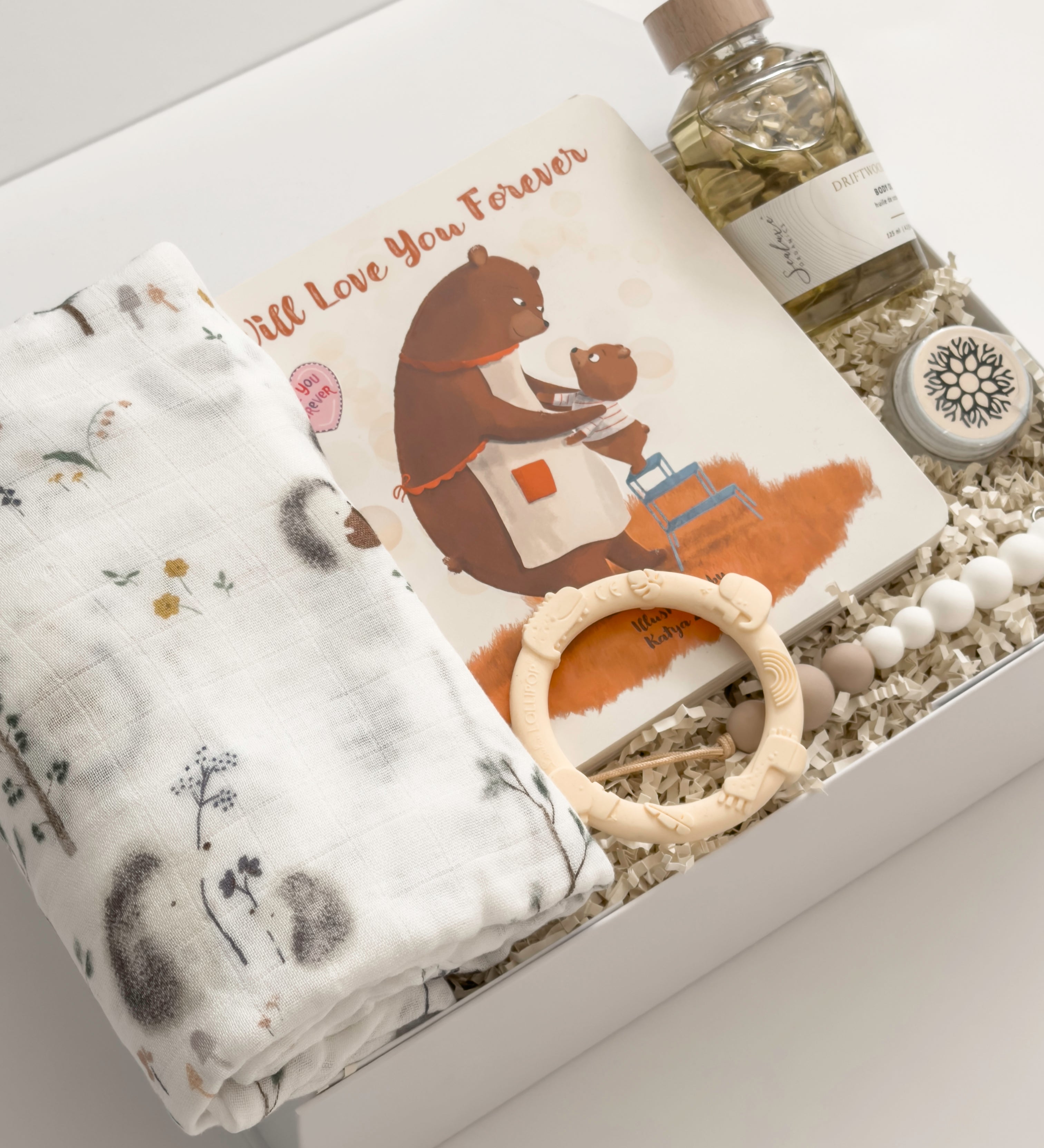 Luxury new baby gift box by Muse Baskets and Co. featuring a Loulou Lollipop swaddle and baby accessories with Canadian-made body care for a new mother.