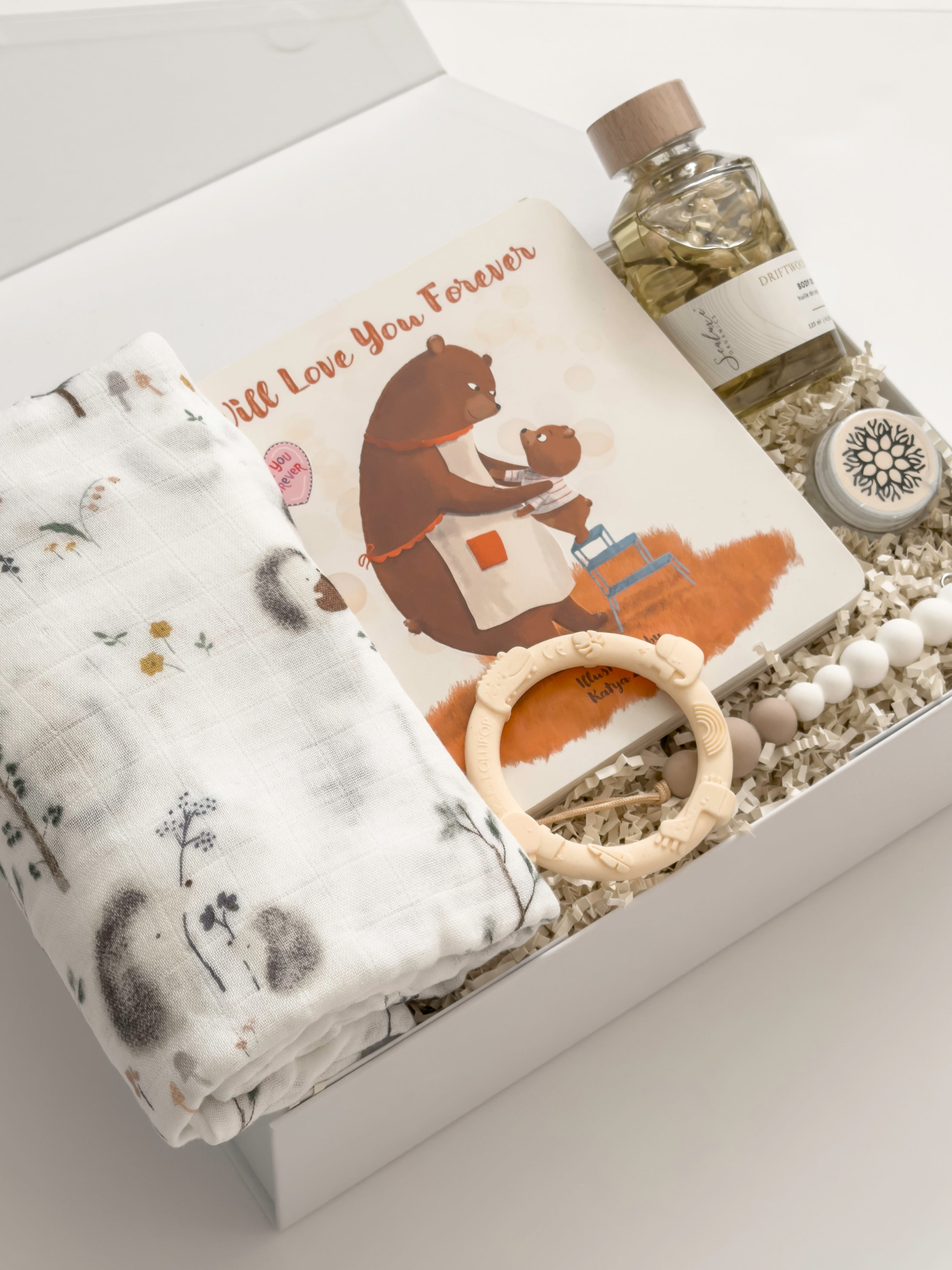 Luxury new baby gift box by Muse Baskets and Co. featuring a Loulou Lollipop swaddle and baby accessories with Canadian-made body care for a new mother.