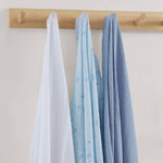 Three baby blankets in white, blue, and gray hanging on a wooden rack against a light background.