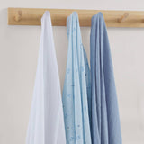 Three baby blankets in white, blue, and gray hanging on a wooden rack against a light background.