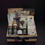 Canadian Gourmet gift box by Muse Baskets and Co., front view of a natural wood crate of Canadian-made chocolate, coffee, cookies, cashews, and preserves finished with a navy satin ribbon, styled as a realtor closing, homeowner welcome, and corporate gift.
