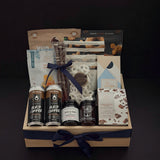 Canadian Gourmet gift box by Muse Baskets and Co., front view of a natural wood crate of Canadian-made chocolate, coffee, cookies, cashews, and preserves finished with a navy satin ribbon, styled as a realtor closing, homeowner welcome, and corporate gift.