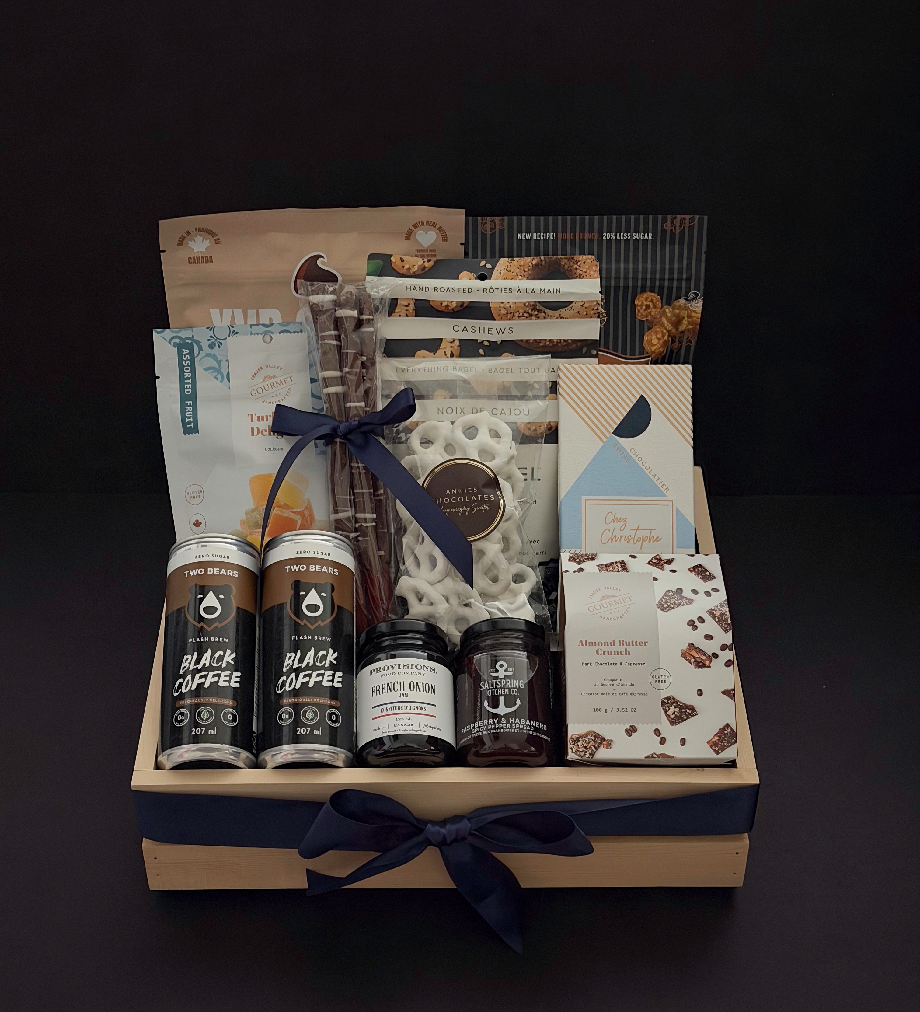 Canadian Gourmet gift box by Muse Baskets and Co., front view of a natural wood crate of Canadian-made chocolate, coffee, cookies, cashews, and preserves finished with a navy satin ribbon, styled as a realtor closing, homeowner welcome, and corporate gift.
