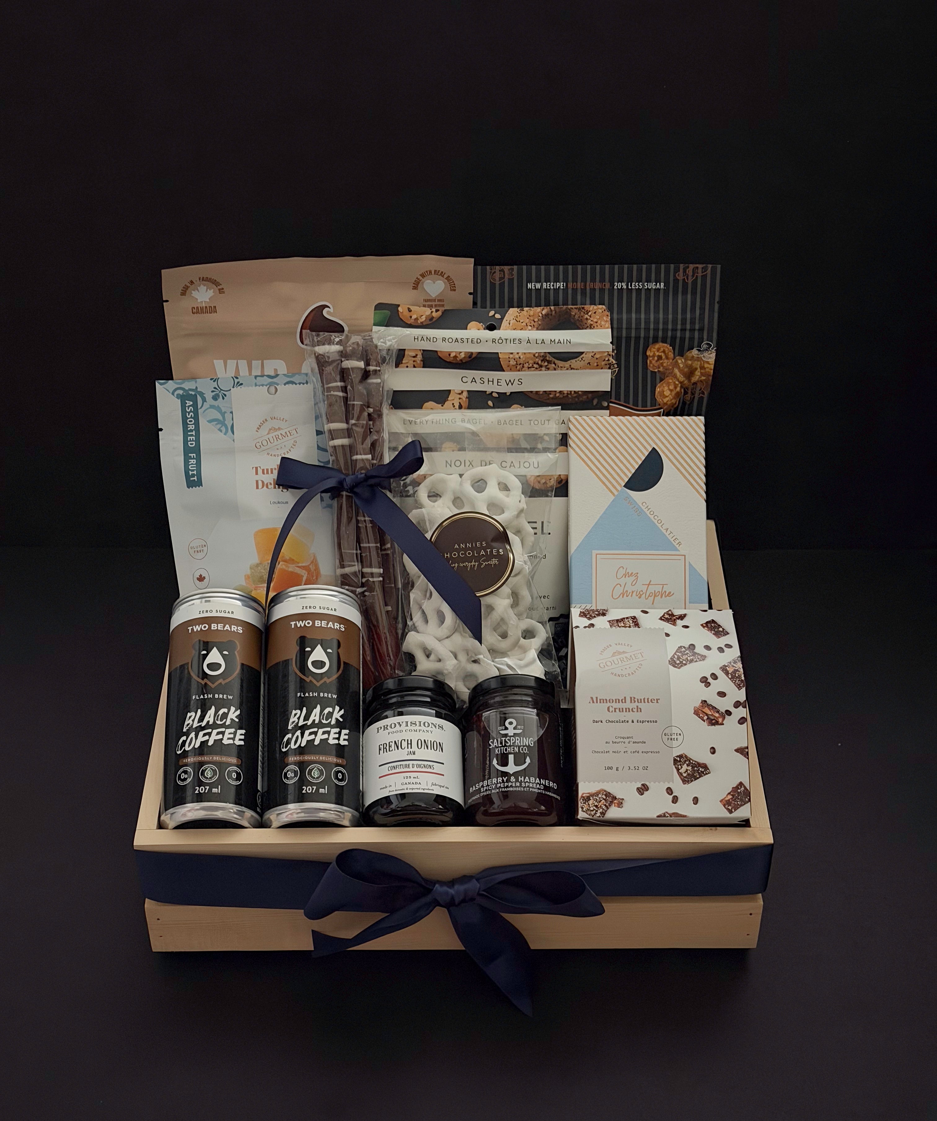 Canadian Gourmet gift box by Muse Baskets and Co., front view of a natural wood crate of Canadian-made chocolate, coffee, cookies, cashews, and preserves finished with a navy satin ribbon, styled as a realtor closing, homeowner welcome, and corporate gift.