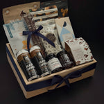 Canadian Gourmet gift box by Muse Baskets and Co. shown at an angle, a wood crate holding Two Bears flash brew coffee, Chez Christophe chocolate, Saltspring Kitchen Co. pepper spread, and white chocolate pretzels tied with a navy satin ribbon for realtor closing and corporate gifting.