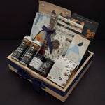 Canadian Gourmet artisan gift box by Muse Baskets and Co., an angled view of a wood crate filled with Canadian small-batch makers including coffee, chocolate bark, French onion jam, and everything bagel cashews, finished with a navy satin ribbon as a homeowner welcome and client appreciation gift.