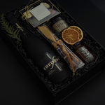 Obsidian Celebration Box with sparkling wine, chocolates, pretzels, honey, and fig spread arranged in a black gift box with festive greenery and ribbon.