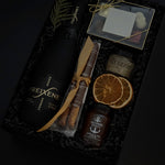 Obsidian Celebration Box with sparkling wine, chocolates, pretzels, honey, and fig spread arranged in a black gift box with festive greenery and ribbon.