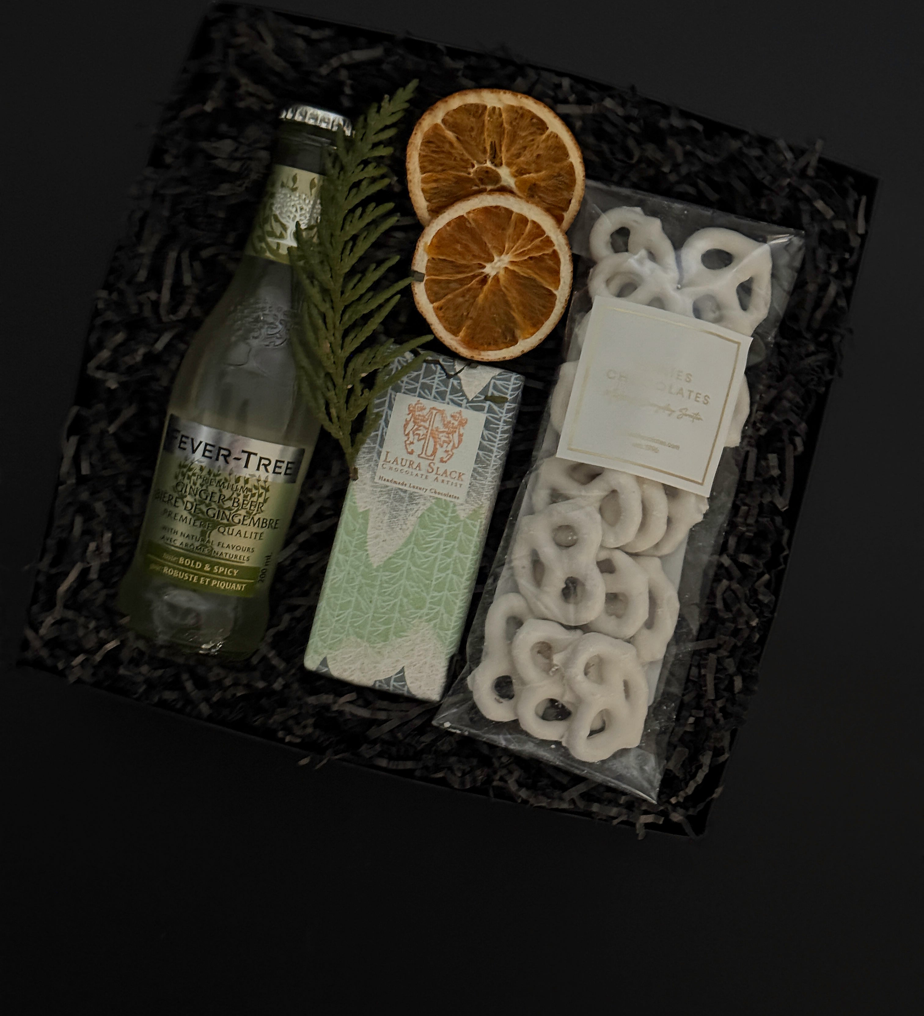 Holiday gift box with Fever-Tree ginger beer, chocolate, white chocolate pretzels and seasonal greenery