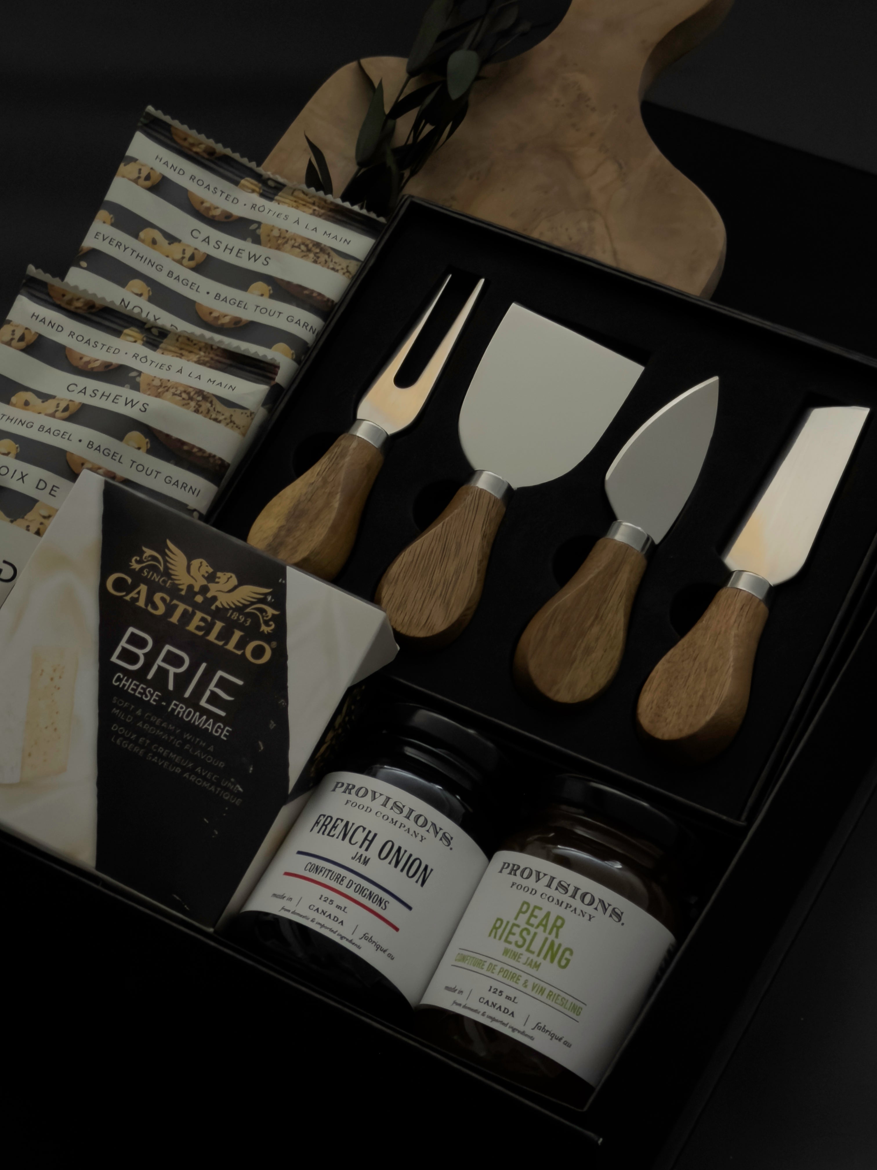 side view of Charcuterie Maison gift box featuring Gharyan Stoneware olive wood board and Provisions Food Company jams