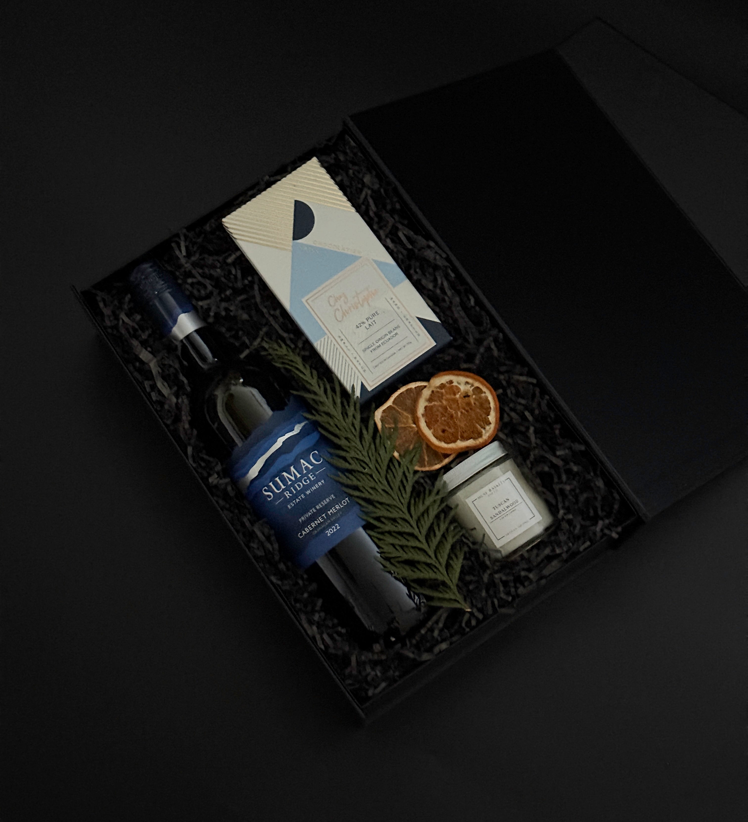 Close-up of artisan chocolate bar and gold tin candle from the Élan Bleu Gift Box, showcasing refined craftsmanship and understated luxury.