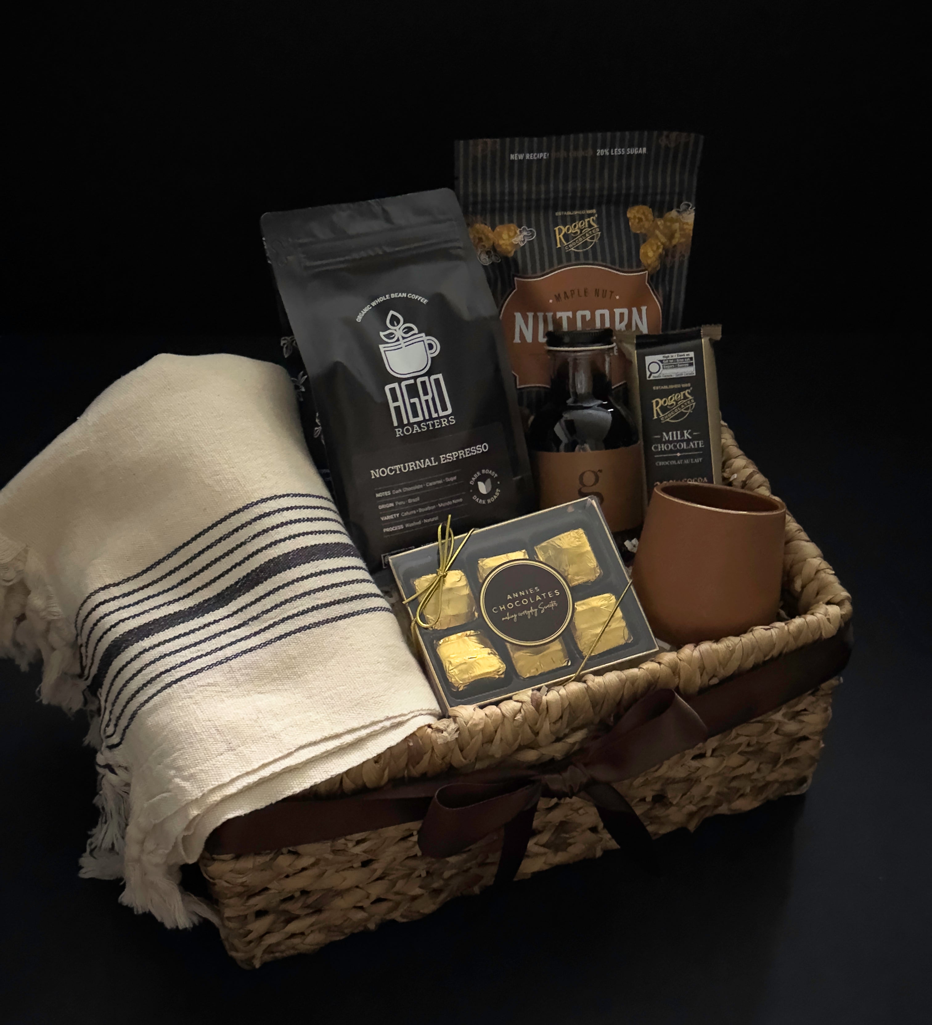Side angle of luxury Canadian coffee gift basket with brown satin ribbon MOA Turkish towel and Roger's Chocolates by Muse Baskets and Co