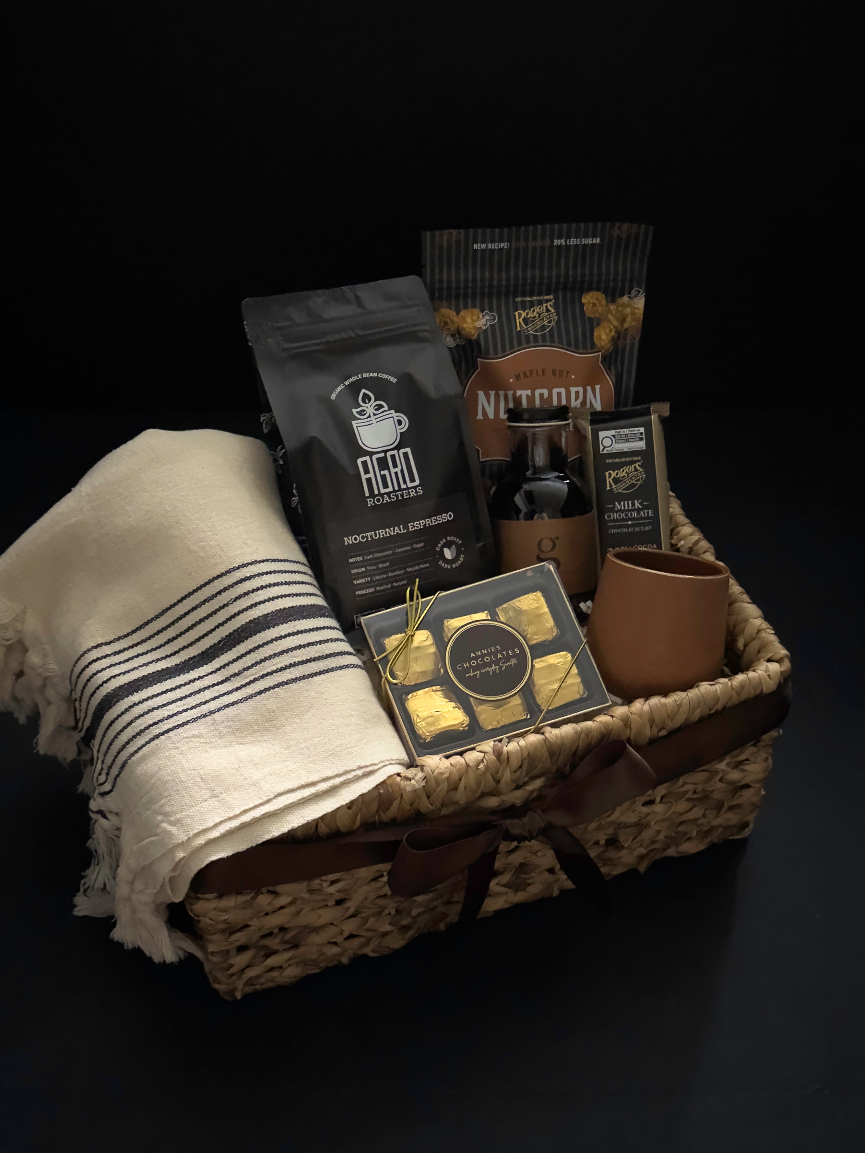 Side angle of luxury Canadian coffee gift basket with brown satin ribbon MOA Turkish towel and Roger's Chocolates by Muse Baskets and Co