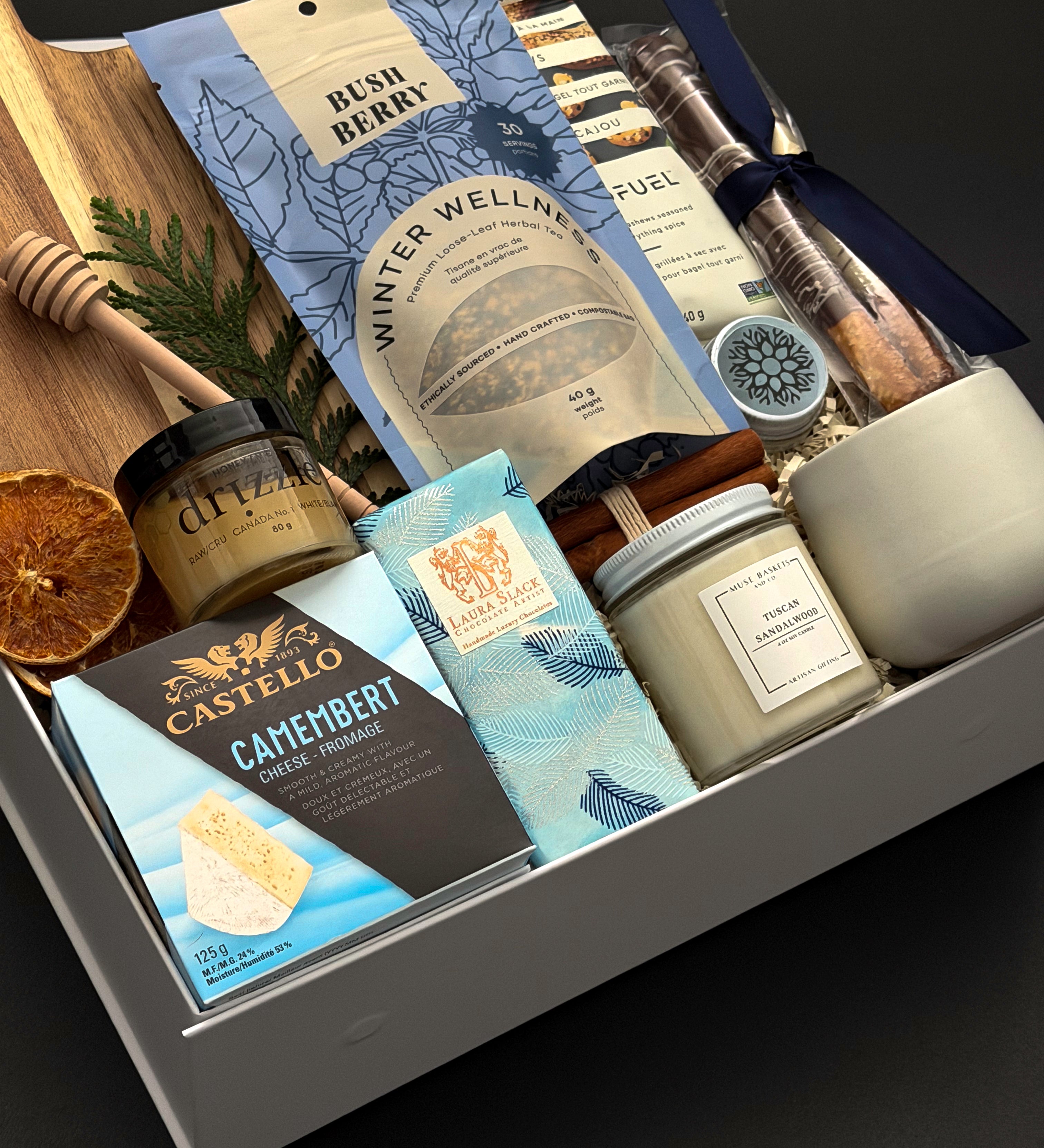 Fireside Provisions corporate holiday gift by Muse Baskets and Co., featuring an acacia board, Winter Wellness Tea and Drizzle honey.