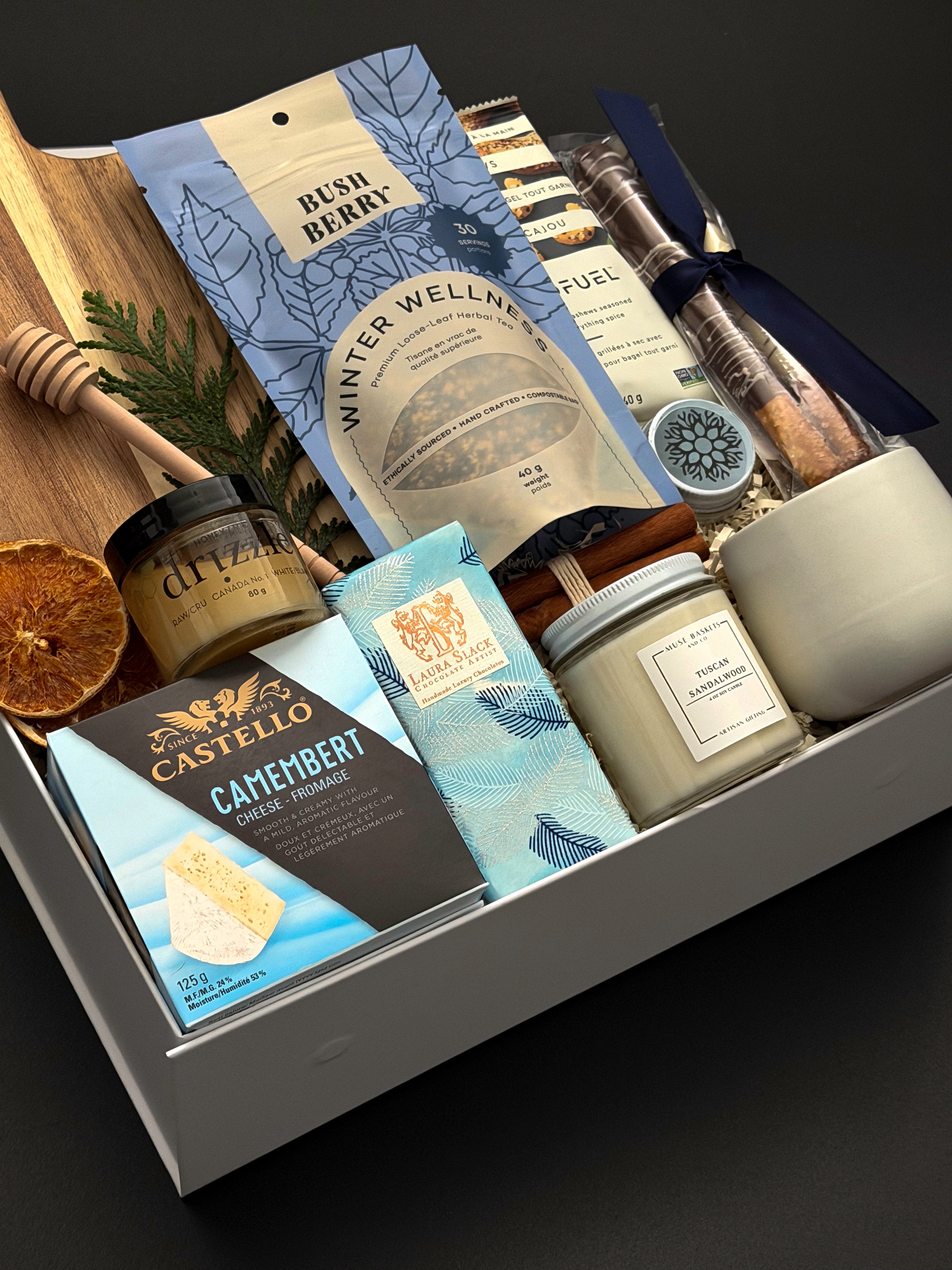 Fireside Provisions corporate holiday gift by Muse Baskets and Co., featuring an acacia board, Winter Wellness Tea and Drizzle honey.