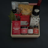 Gift basket with various items including a bottle, pretzels, and snacks on a dark background