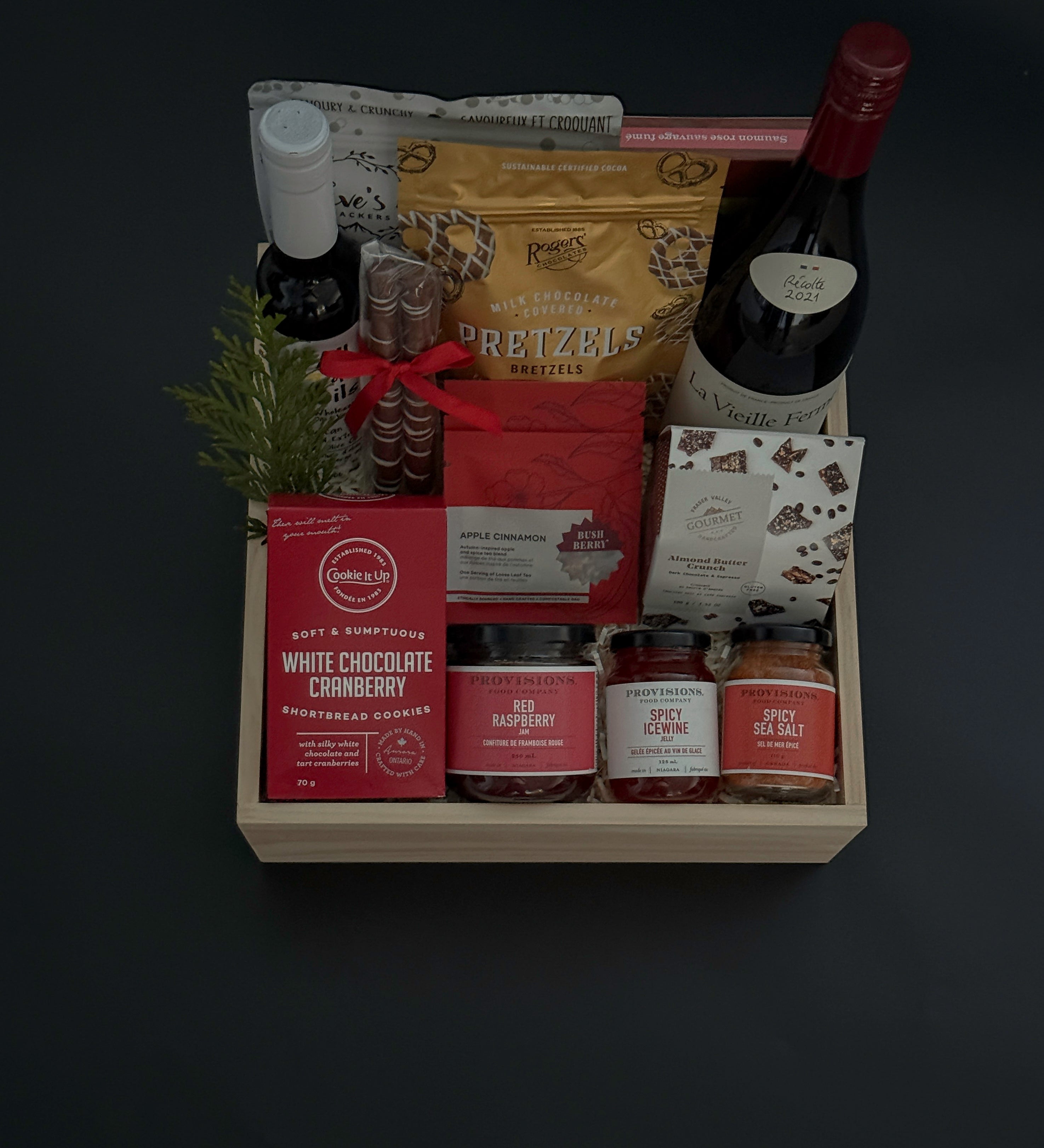 Gift basket with various items including a bottle, pretzels, and snacks on a dark background