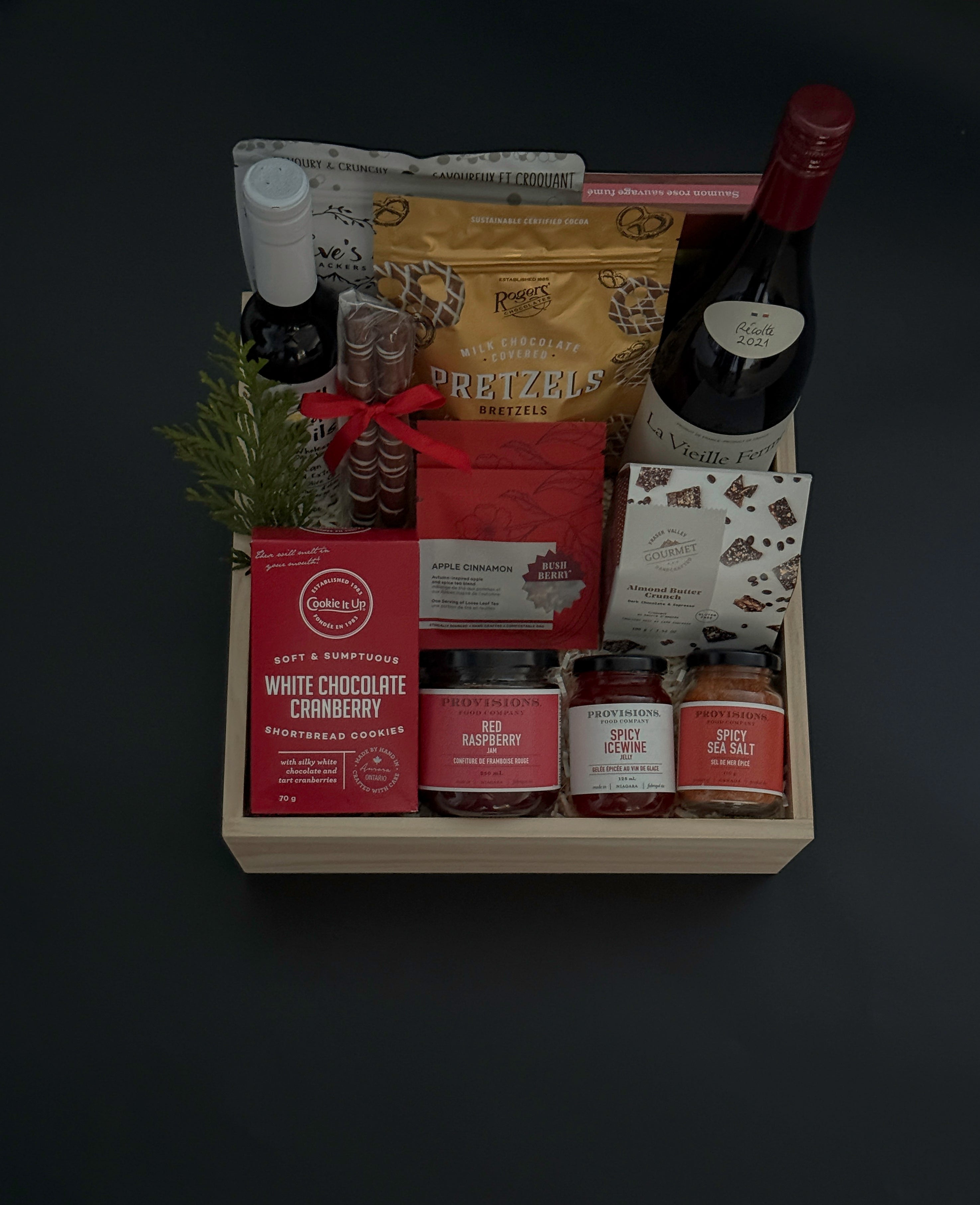 Gift basket with various items including a bottle, pretzels, and snacks on a dark background