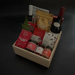 Gift basket with various items including a bottle of wine on a dark background