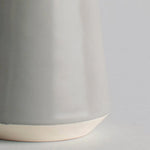Close-up of a gray ceramic cup with a beige base on a light gray background