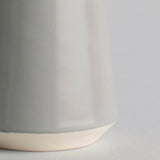 Close-up of a gray ceramic cup with a beige base on a light gray background