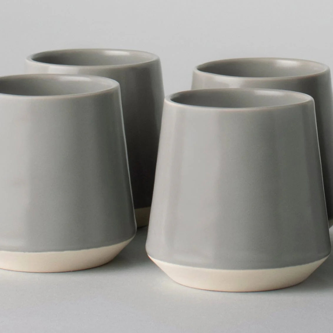 Four gray ceramic cups with a white on a light gray background