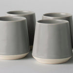 Four gray ceramic cups with a white on a light gray background