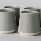 Four gray ceramic cups with a white on a light gray background