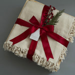Closed gift box with cream blanket and holiday decorations, perfect for  corporate clients and colleagues.