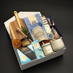 Fireside Provisions holiday gift box by Muse Baskets and Co., with tea, honey, artisan chocolate and stoneware in a Signature Pearl White gift box.