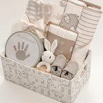 side view of curated newborn gift basket with Loulou Lollipop swaddle and My Little Print keepsake kit