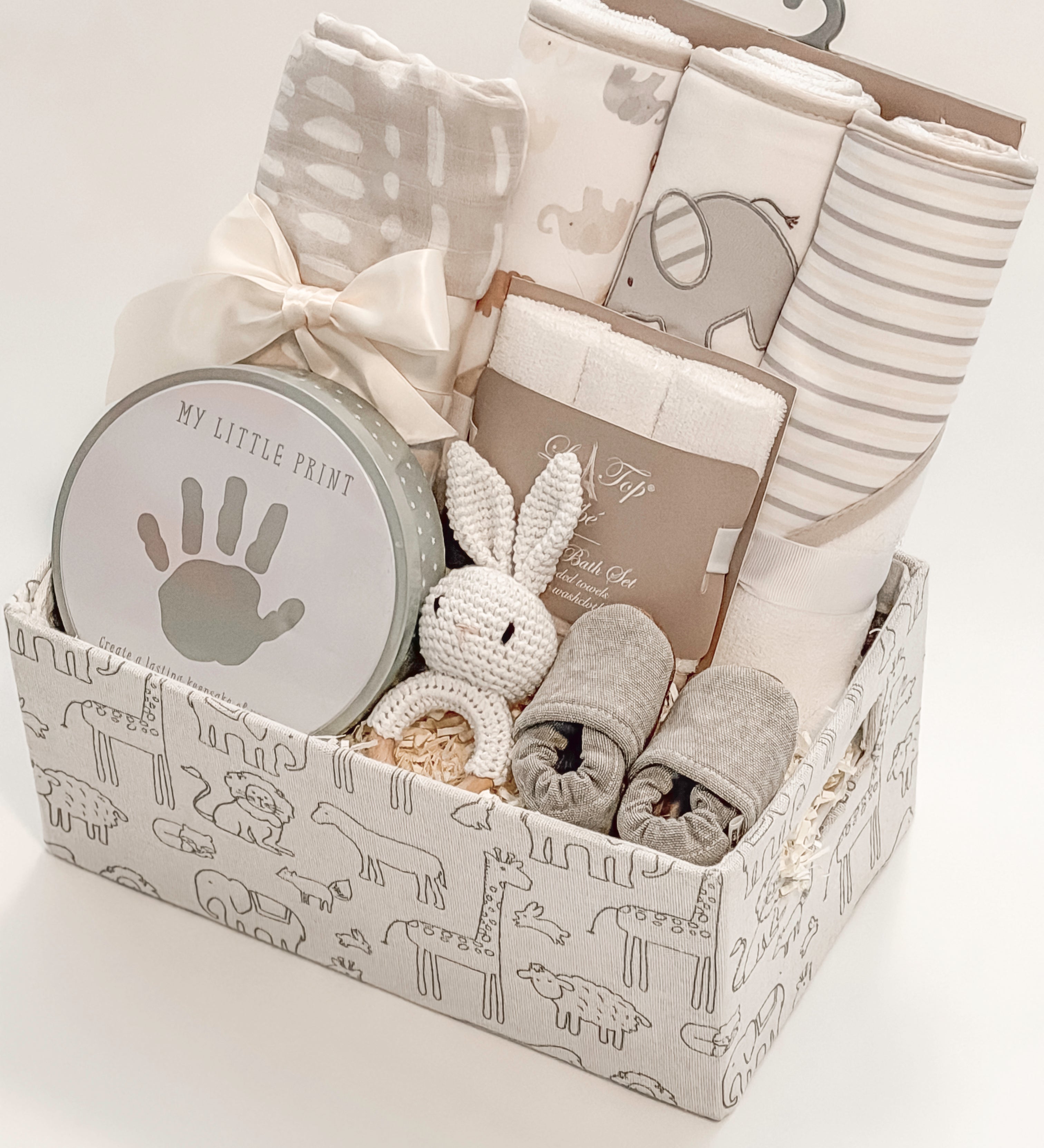 side view of curated newborn gift basket with Loulou Lollipop swaddle and My Little Print keepsake kit