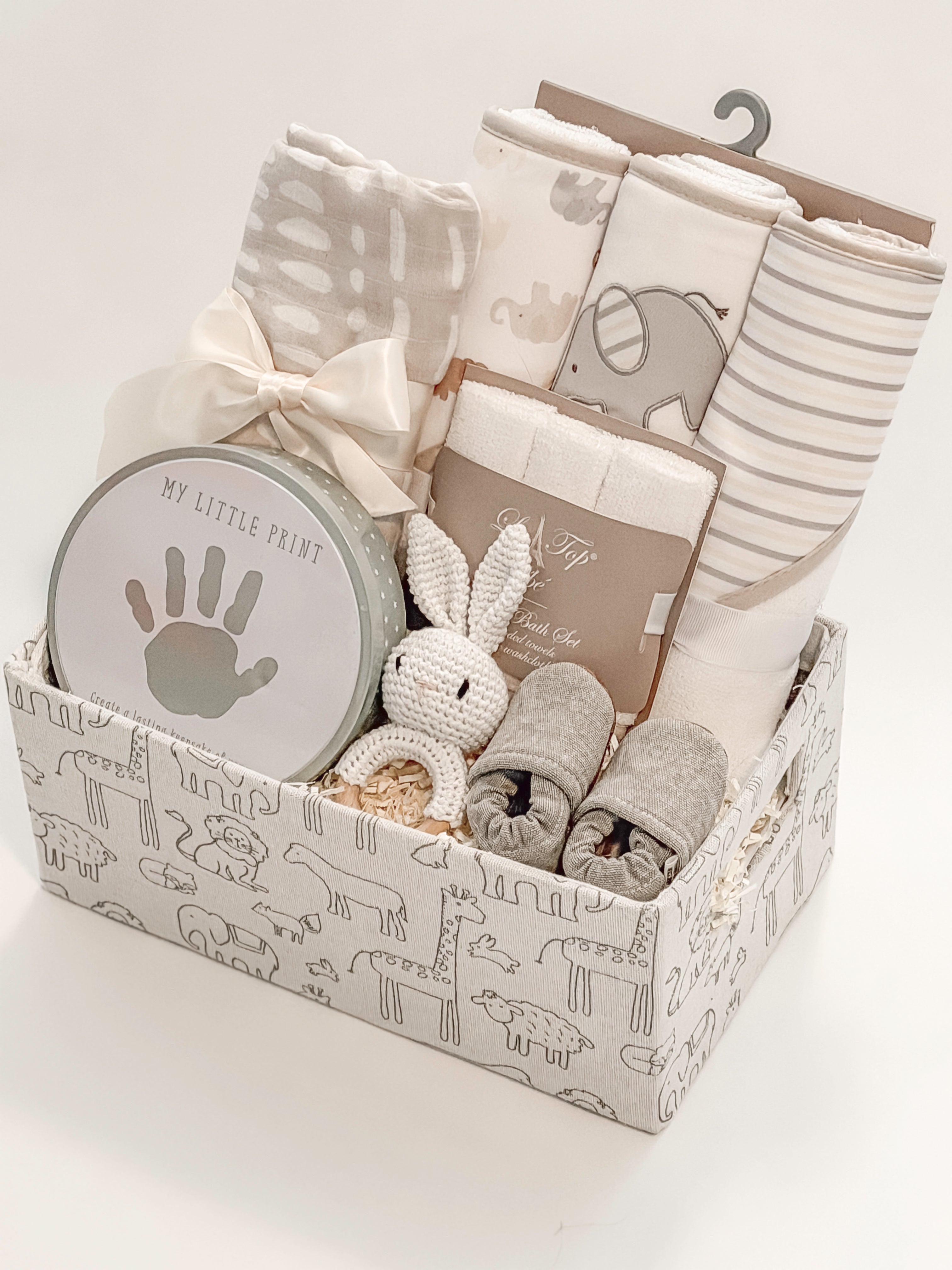 side view of curated newborn gift basket with Loulou Lollipop swaddle and My Little Print keepsake kit
