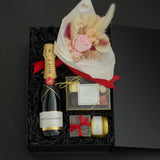 Luxury champagne gift box featuring Moët & Chandon, preserved florals, gourmet chocolates, and candle in a signature black gift box