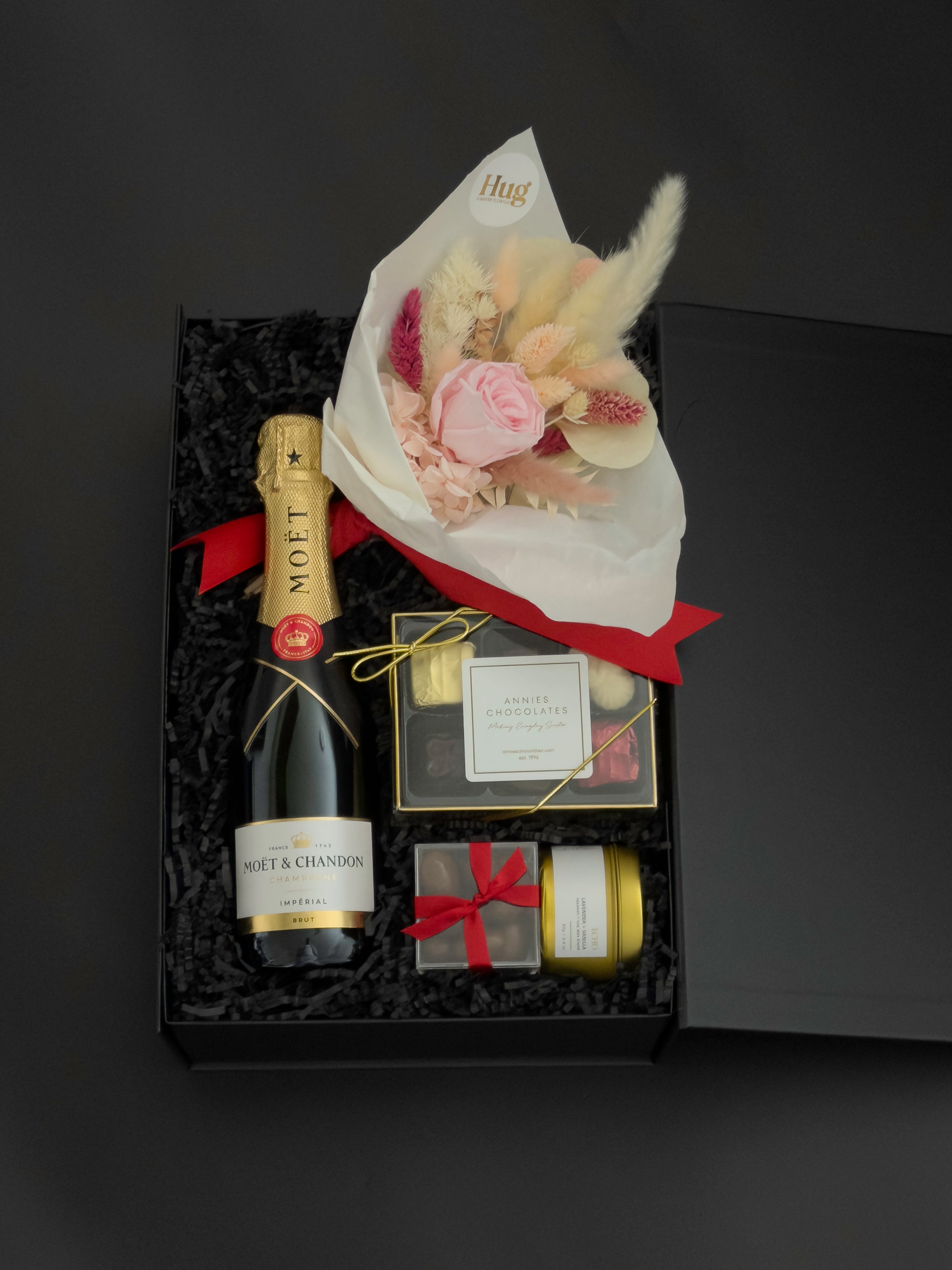 Luxury champagne gift box featuring Moët & Chandon, preserved florals, gourmet chocolates, and candle in a signature black gift box
