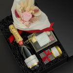 Elegant black gift box with Moët & Chandon champagne, preserved floral bouquet, chocolates, and candle arranged for a romantic celebration