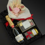 Elegant black gift box with Moët & Chandon champagne, preserved floral bouquet, chocolates, and candle arranged for a romantic celebration