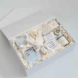 Gift set with candles, soap, and other items in a white box on a light gray background