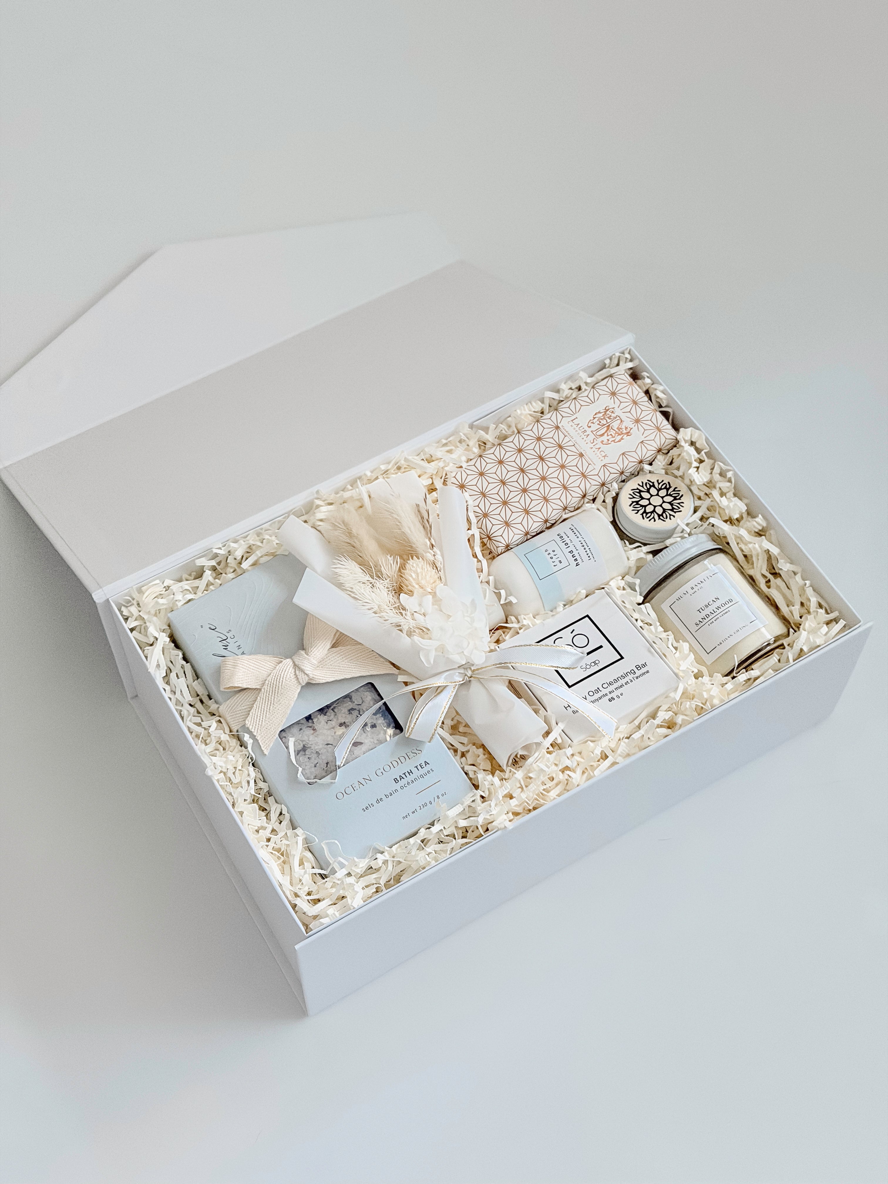 Gift set with candles, soap, and other items in a white box on a light gray background