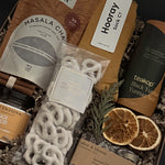 Holiday comfort gift box with cozy self-care items, winter greenery and cinnamon accents.