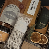 Holiday comfort gift box with cozy self-care items, winter greenery and cinnamon accents.