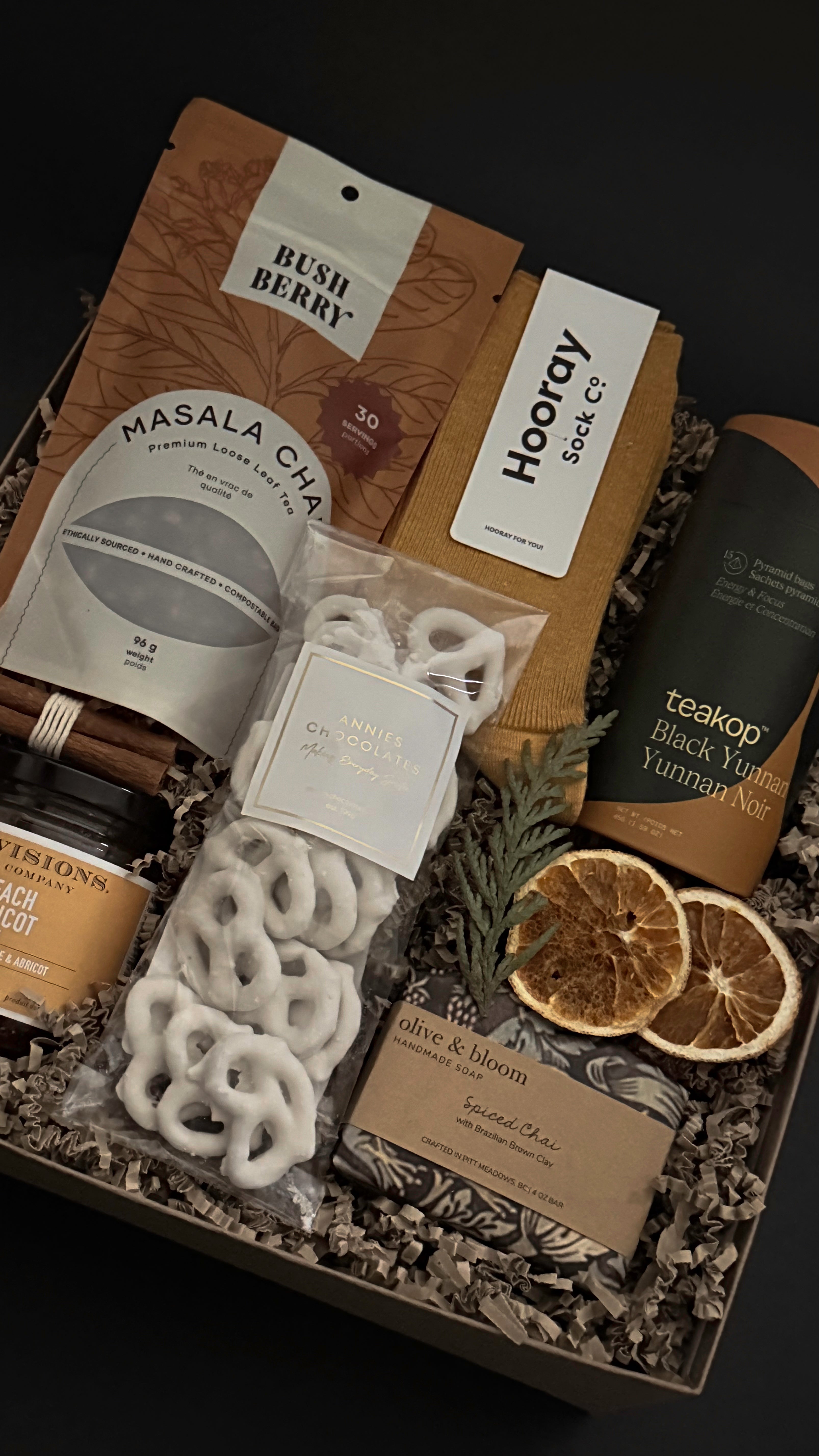 Holiday comfort gift box with cozy self-care items, winter greenery and cinnamon accents.