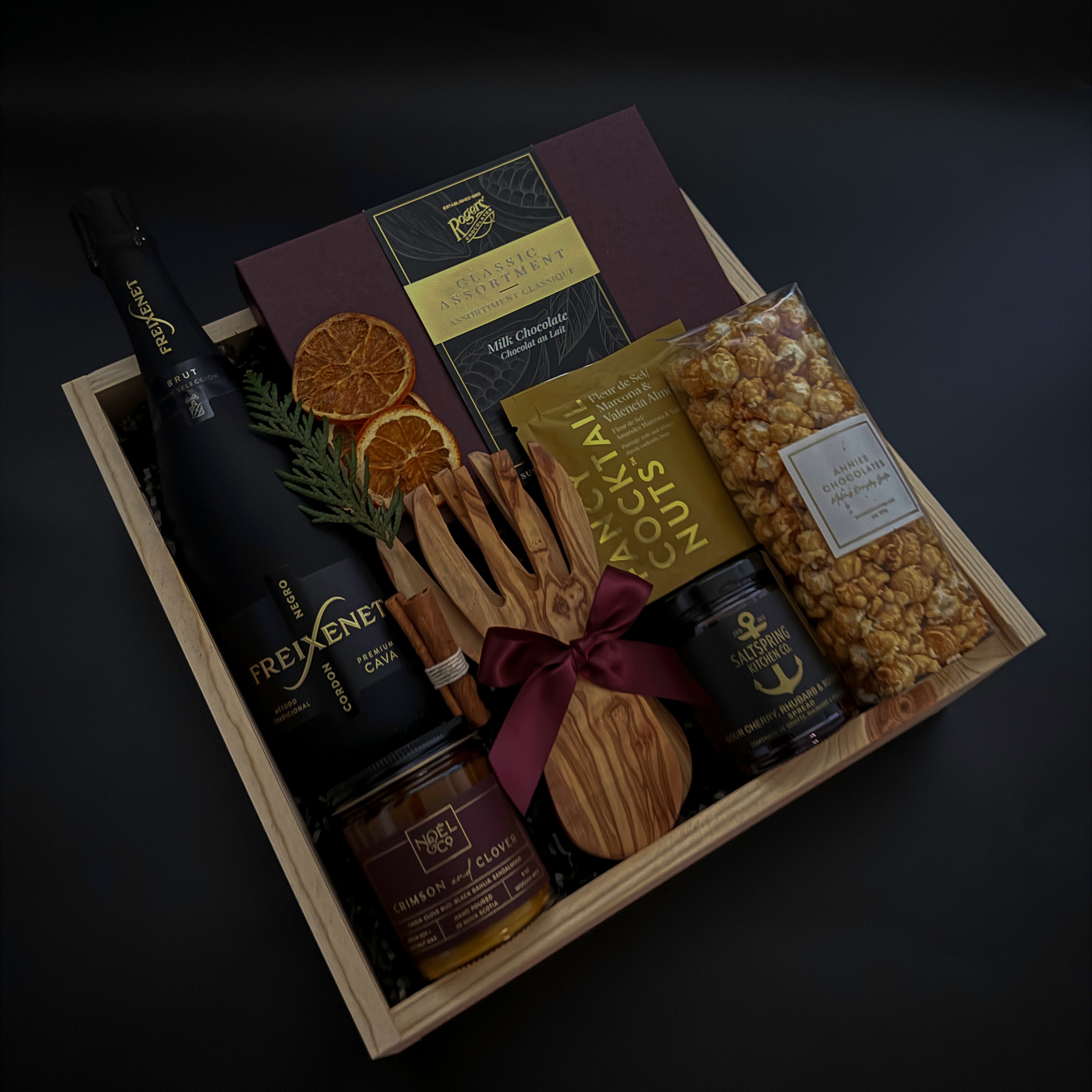 Gift basket with snacks, drinks, and decorative items on a dark background