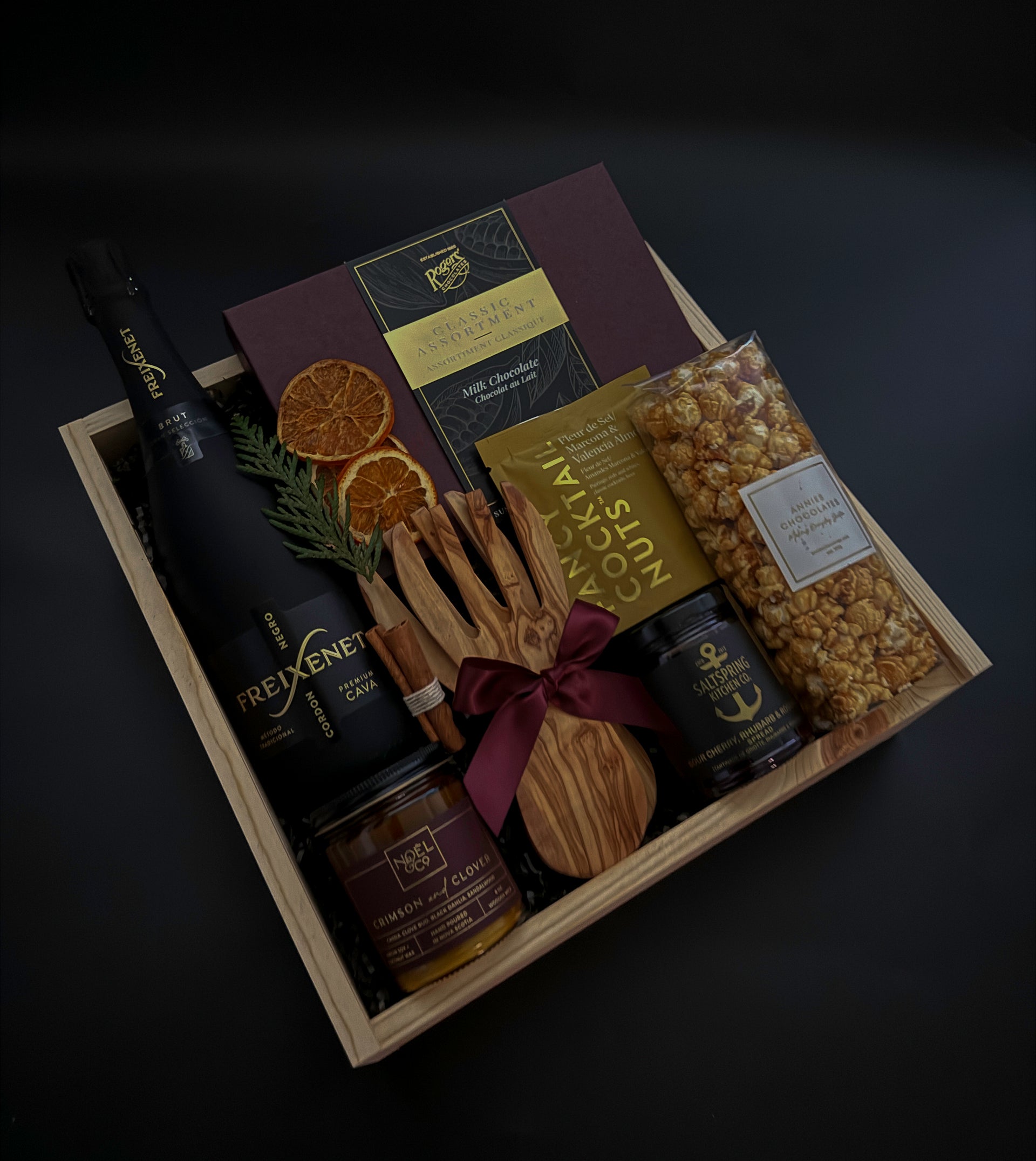 Gift basket with snacks, drinks, and decorative items on a dark background