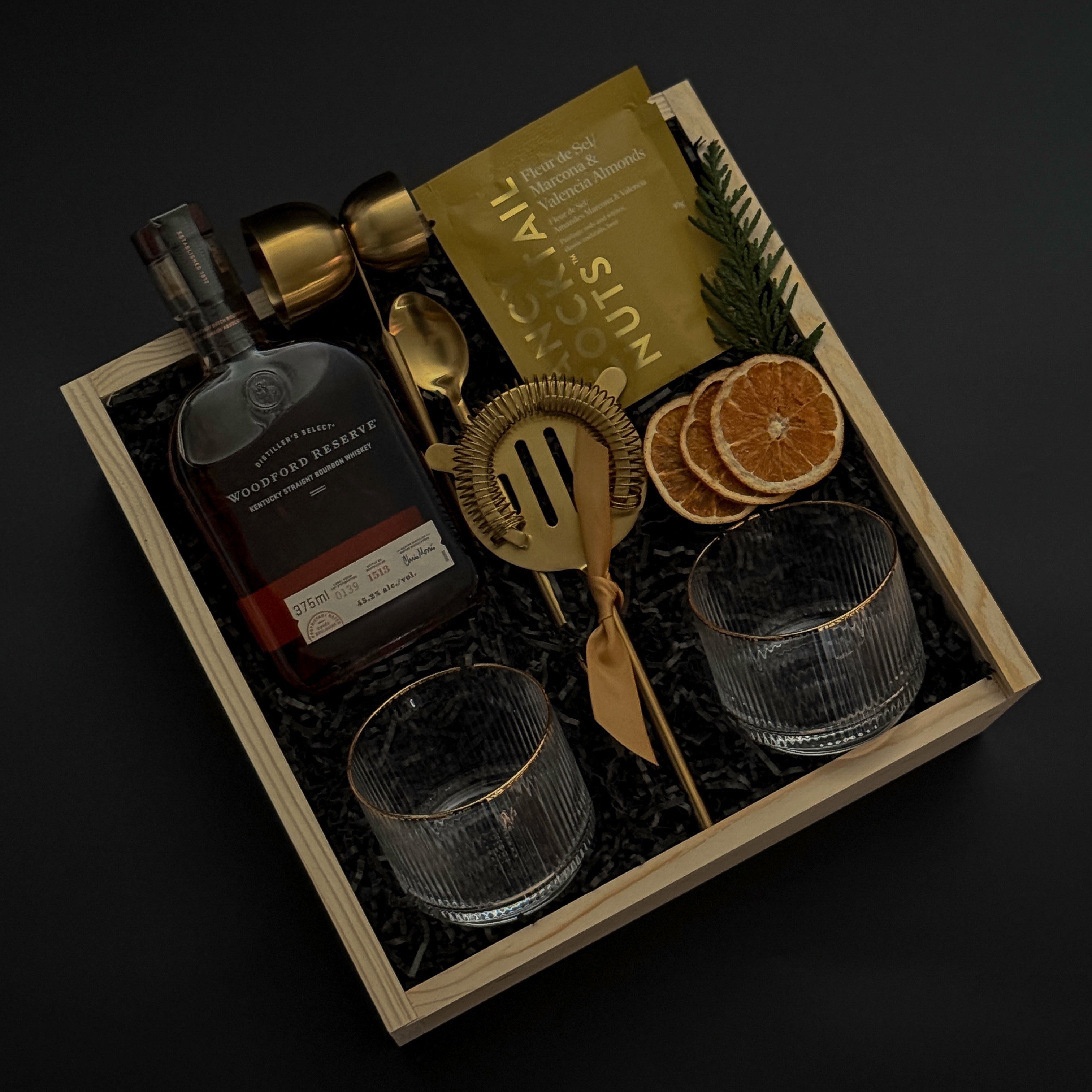 Gift set with a bottle, glasses, and decorative items on a dark background