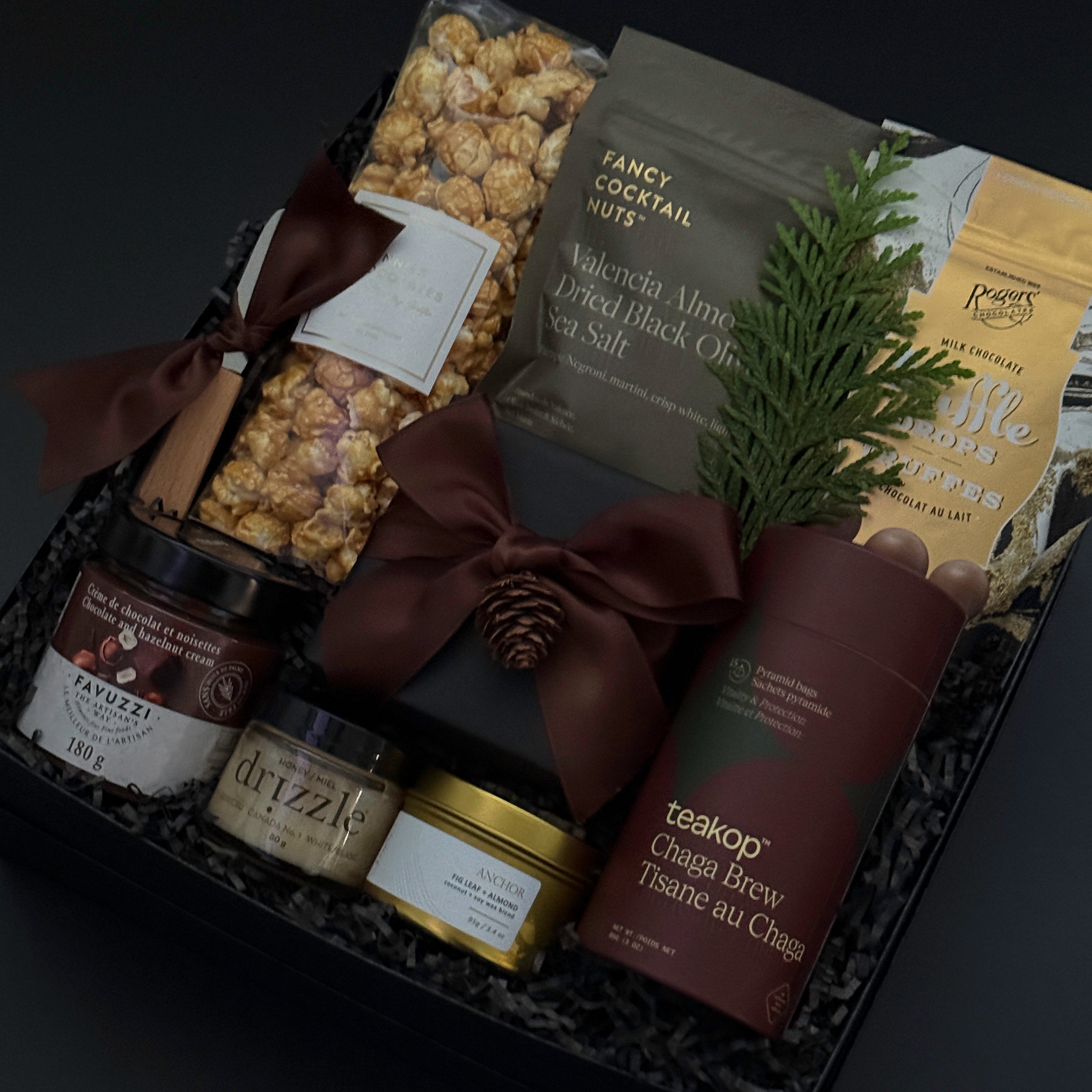 Gourmet gift basket with snacks, coffee, and a bottle on a dark background